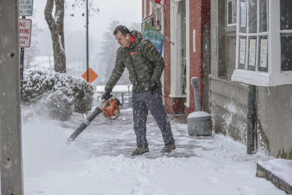 Byrum Geisler removes snow from a portion of sidewalk on Main Street in Abingdon, Va., as snow continues to fall Monday afternoon, Jan. 15, 2024. (Emily Ball/Bristol Herald Courier via AP)