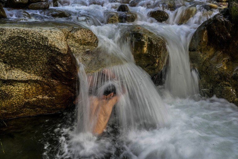 A Kashmiri man cools off at a stream on a hot summer day on the outskirts of Srinagar, Indian controlled Kashmir, Tuesday, July 4, 2023. The entire planet sweltered for the two unofficial hottest days in human recordkeeping Monday and Tuesday, according to University of Maine scientists at the Climate Reanalyzer project. The unofficial heat records come after months of unusually hot conditions due to climate change and a strong El Nino event. (AP Photo/Mukhtar Khan)