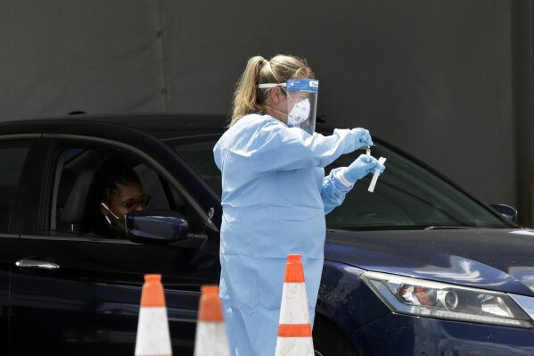 A healthcare worker puts a test swab into a vial after testing a passenger at a drive-through coronavirus testing site outside of Hard Rock Stadium, Friday, June 26, 2020, in Miami Gardens, Fla. Florida banned alcohol consumption at its bars Friday as its daily confirmed coronavirus cases neared 9,000, a new record that is almost double the previous mark set just two days ago. (AP Photo/Wilfredo Lee)