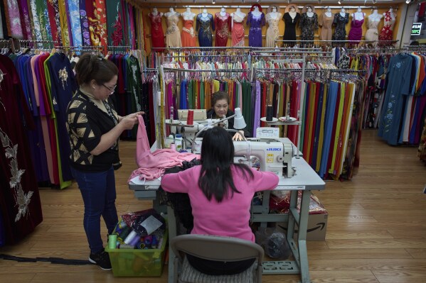 Three Vietnamese women work in a traditional dress shop in the Little Saigon neighborhood of Westminster, Calif., Saturday, April 26, 2025. (AP Photo/Jae C. Hong)