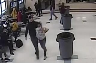 In this frame grab from surveillance video provided by the Kenosha Unified School District, an off-duty police officer escorts a 12-year-old student out of a school cafeteria following a lunchtime fight, in Kenosha, Wis., on March 4, 2022. Earlier in the video, the officer, who was working as a security guard, is shown intervening in the fight and putting his knee on the girl’s neck to restrain her. (Kenosha Unified School District via AP)