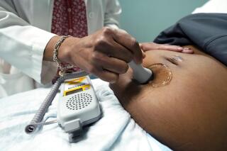 FILE - A doctor uses a hand-held Doppler probe on a pregnant woman to measure the heartbeat of the fetus on Dec. 17, 2021, in Jackson, Miss. U.S. births were flat in 2022, as the nation continues to see fewer babies born than before the pandemic. (AP Photo/Rogelio V. Solis, File)