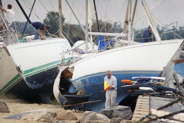 FILE - Boat owners gather their belongings along the shore in Dartmouth, Mass., Aug. 20, 1991, after Hurricane Bob swept through southern Massachusetts. New England is known for its fickle weather, powerful nor'easters and blizzards. Destructive hurricanes, however, are relatively rare and typically don't pack the same punch as tropical cyclones that hit the Southeast. Hurricanes usually lose some steam, becoming tropical storms, or extratropical storms, in northern waters. (AP Photo/Susan Walsh, File)