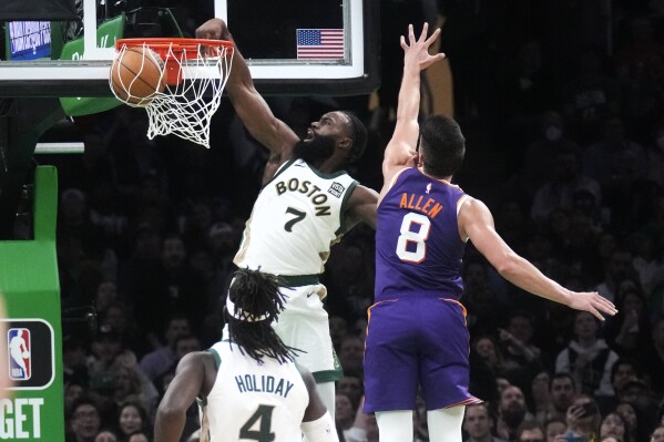 El escolta de los Celtics de Boston, Jaylen Brown (7), clava después de superar al escolta de los Suns de Phoenix, Grayson Allen (8), durante la segunda mitad de un partido de baloncesto de la NBA, el jueves 14 de marzo de 2024, en Boston. (AP Foto/Charles Krupa)