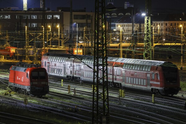 A suburban train and an electric locomotive stand on sidings at Leipzig Central Station in the early morning in Leipzig, Germany, Monday Dec. 18, 2023. Members of a union representing German train drivers have voted overwhelmingly to stage open-ended strikes in a bitter dispute with the main national railway operator over working hours and pay, union leaders said Tuesday, Dec. 19, 2023. (Jan Woitas/dpa via AP)
