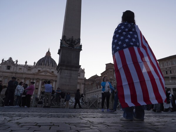 Andrea Gallardo, 20, from Texas, wears an American flag after Pope Leo XIV appeared on the balcony of St Peter's Basilica following his election, at the Vatican, Thursday, May 8, 2025. (AP Photo/Paolo Santalucia)