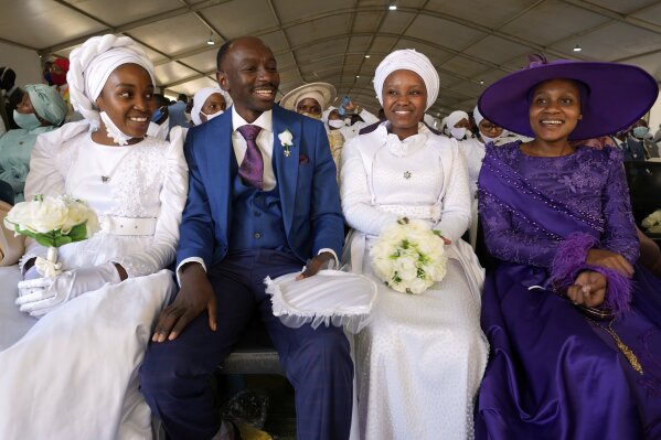 A man with his wife and two of his brides sits inside a marquee ahead of the mass Easter weddings for 3,000 people, some polygamous, at the International Pentecost Holiness Church in Heidelberg, east of Johannesburg, South Africa, Sunday, April 20, 2025. (AP Photo/Themba Hadebe)