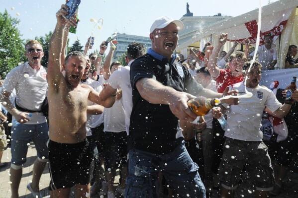 FILE -English soccer fans spray beer before the group D match between England and France during the Euro 2012 soccer championship in Donetsk, Ukraine, Ukraine, Monday, June 11, 2012. The message to English soccer fans at Euro 2024 is clear: behave or else. A range of measures are being taken to avoid or clamp down on trouble from England supporters at the monthlong tournament in Germany, which kicks off on Friday. (AP Photo/Sergei Chuzavkov, File)