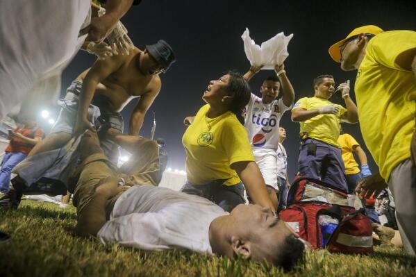 Rescuers attend an injured fan lying on the field of the Cuscatlan stadium in San Salvador, El Salvador, Saturday, May 20, 2023. At least nine people were killed and dozens more injured when stampeding fans pushed through one of the access gates at a quarterfinal Salvadoran league soccer match between Alianza and FAS. (AP Photo/Milton Flores)