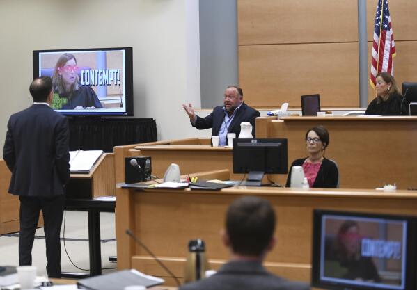 Conspiracy theorist Alex Jones is shown a photo of Judge Barbara Bellis with laser beams coming out of her eyes from his website during his testimony as Judge Bellis listens beside him, right, during the Sandy Hook defamation damages trial at Connecticut Superior Court in Waterbury, Conn. Thursday, Sept. 22, 2022. Jones was found liable last year by default for damages to plaintiffs without a trial, as punishment for what the judge called his repeated failures to turn over documents to their lawyers. The six-member jury is now deciding how much Jones and Free Speech Systems, Infowars’ parent company, should pay the families for defaming them and intentionally inflicting emotional distress. (Tyler Sizemore/Hearst Connecticut Media via AP, Pool)