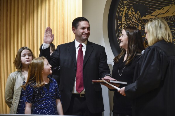 FILE - Montana Attorney General Austin Knudsen, center, is sworn into office, Jan. 4, 2021, inside the state Capitol in Helena, Mont. Knudsen faces 41 counts of professional misconduct after a special counsel alleged he and attorneys in his office defied state Supreme Court orders and questioned the impartiality of the Court in what became a legal battle over the subpoena powers of the Legislature. A spokeswoman for Knudsen said the complaint filed Tuesday, Sept. 5, 2023, is meritless and politically motivated as Knudsen seeks re-election next year. (Thom Bridge/Independent Record via AP, File)