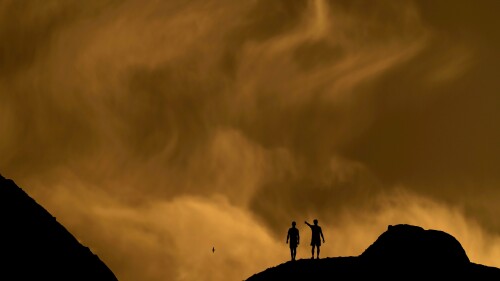 FILE - People watch the sunset from a peak at Papago Park, Feb. 19, 2021, in Phoenix. (AP Photo/Charlie Riedel, File)