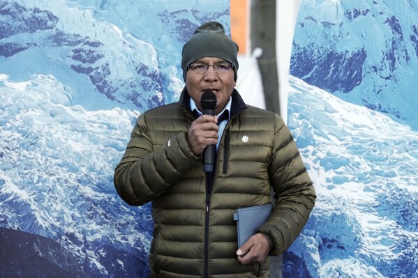 Peruvian farmer Luciano Lliuya speaks to the media in front of glacier pictures held by activists at the Higher Regional Court in Hamm, Germany, before a first hearing of his climate damages case against the German energy company RWE for its carbon emissions, which may have been contributing to the melting of a nearby glacier that could flood his home, Monday, March 17, 2025. (AP Photo/Martin Meissner)