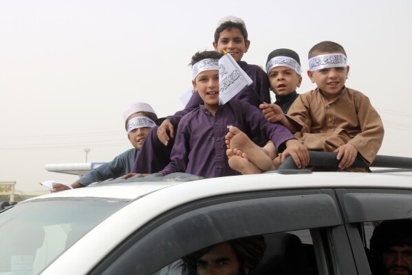 Children hold Taliban flags during a celebration marking the second anniversary of the withdrawal of U.S.-led troops from Afghanistan, in Kandahar, south of Kabul, Afghanistan, Tuesday, Aug. 15, 2023. (AP Photo/Abdul Khaliq)