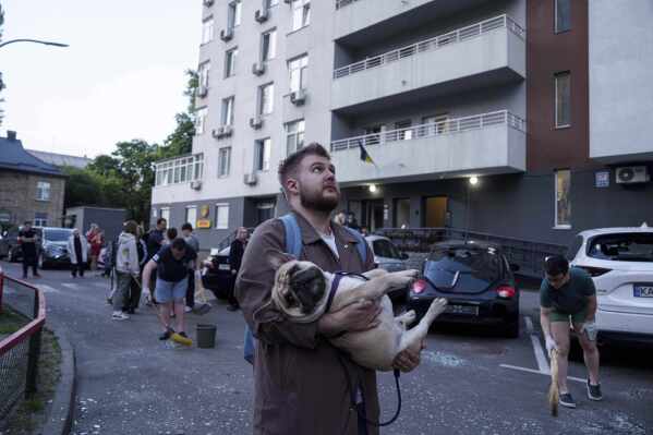 Un hombre lleva a su perro frente a un edificio residencial de varios pisos dañado tras un ataque con drones rusos en Kiev, Ucrania, el viernes 6 de junio de 2025. (Foto AP/Evgeniy Maloletka)