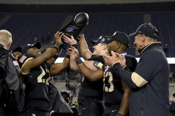 Army head coach Jeff Monken, right, looks on as his team celebrate with the trophy after their win in the Armed Forces Bowl NCAA college football game against Missouri in Fort Worth, Texas, Wednesday, Dec. 22, 2021. (AP Photo/Emil Lippe)