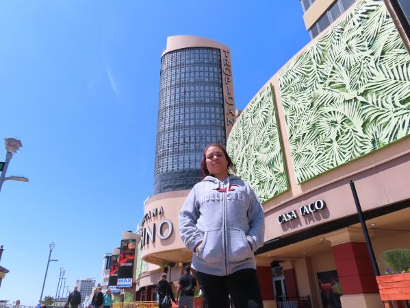 Janey Negron, a bartender at the Tropicana Casino in Atlantic City N.J., stands outside her workplace on April 29, 2022. Negron, who has five children and takes care of her mother, says daily expenses are rising, and says Atlantic City casino workers need a raise in contract talks that are currently under way. (AP Photo/Wayne Parry)
