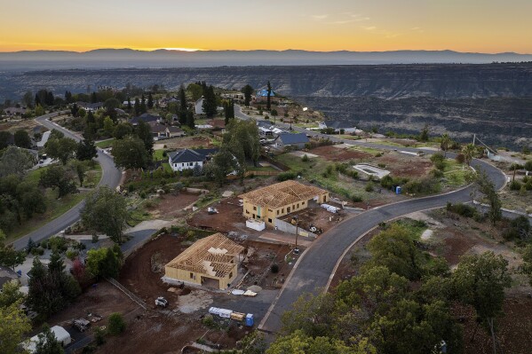 The sun sets over Valley Ridge Drive, Thursday, Oct. 26, 2023, in Paradise, Calif. Empty lots, homes under construction and residences built after the Camp Fire line the street. (AP Photo/Noah Berger)