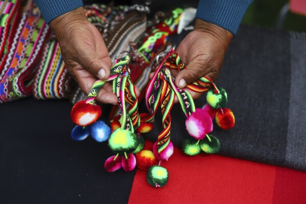 An Aymara Indigenous woman shows handwoven woolen crafts made on the sidelines of a fashion show showcasing Indigenous creations at Zofri Mall in Iquique, Chile, Saturday, July 29, 2023. The Agricultural Development Institute of Chile organized the show to boost camelid farming and craft sales. (AP Photo/Ignacio Munoz)