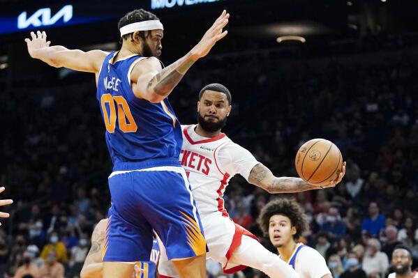 Houston Rockets guard D.J. Augustin, front right, passes the ball to a teammate as Phoenix Suns center JaVale McGee (00) defends during the first half of an NBA basketball game Thursday, Nov. 4, 2021, in Phoenix. (AP Photo/Ross D. Franklin)