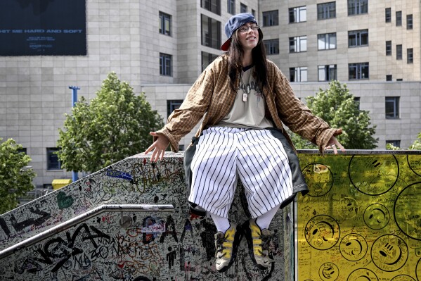 US singer Billie Eilish is sitting on a ledge of a staircase railing known as the "Billie Eilish wall", in Berlin Friday, June 7, 2024. The artist wants to draw attention to her new album "hit me hard and soft" during a promotional campaign. (Britta Pedersen/dpa via AP)