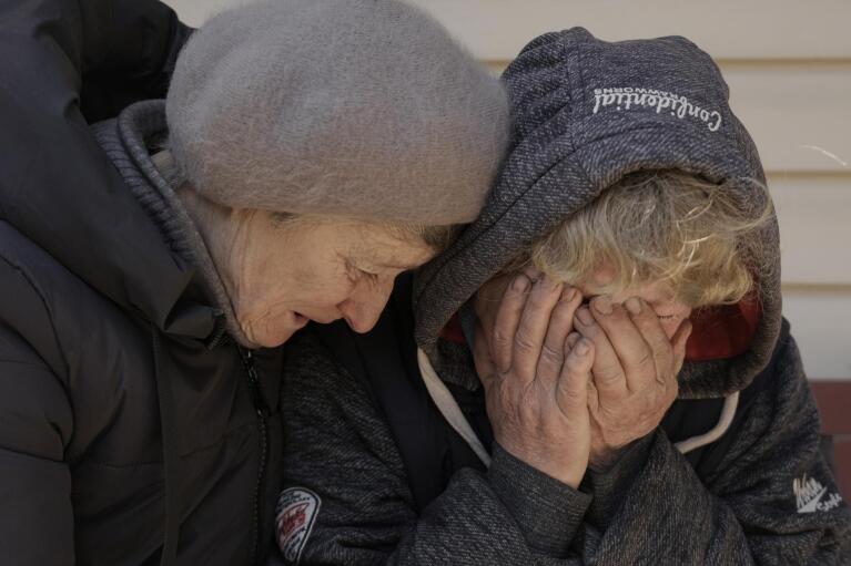 FILE - A neighbor comforts Natalya, whose husband and nephew were killed by Russian forces, as she cries in her garden in Bucha, Ukraine, Monday, April 4, 2022. (AP Photo/Vadim Ghirda, File)