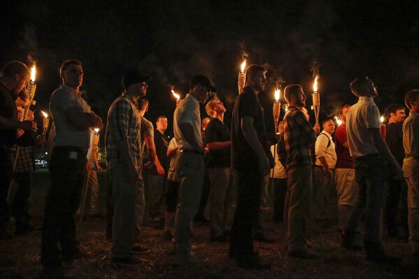 FILE - Multiple white nationalist groups march with torches through the University of Virginia campus on Aug. 11, 2017, in Charlottesville, Va. Nearly seven years after a large gathering of white nationalists erupted in violence in Charlottesville, Virginia, a trial is set to begin for one of about a dozen people who were charged with using flaming torches to intimate counter protesters. (Mykal McEldowney/The Indianapolis Star via AP, File)
