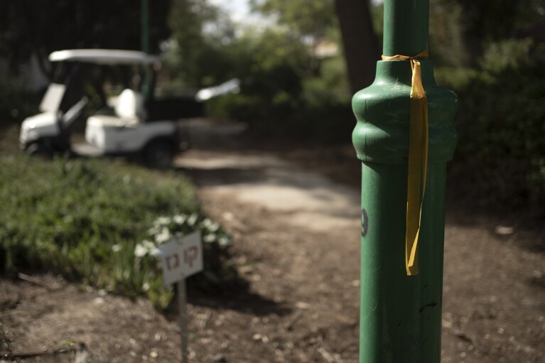 A yellow ribbon for the hostages taken by Hamas is tied to a pole in Kibbutz Nir Oz, near the Israel-Gaza border, on Nov. 21, 2023. An Associated Press review of hundreds of messages shared among Nir Oz residents, security camera footage and Hamas instruction manuals show the group planned ahead of time to target civilians. (AP Photo/Maya Alleruzzo)