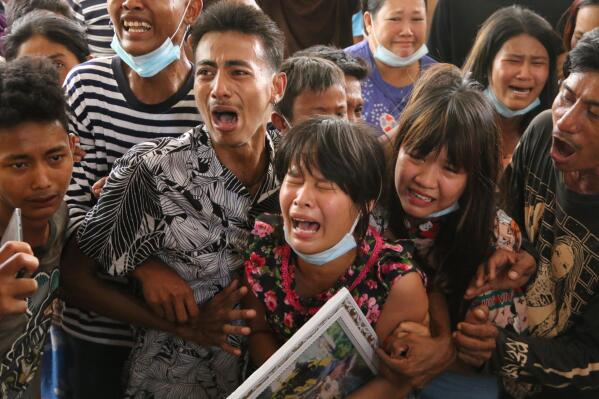 In this April 1, 2021 photo provided by Dawei Watch news outlet, Hnin Twel Tar Aung, girlfriend of 17-year old Kyaw Min Latt, cries while holding his photo before his cremation in Dawei, Myanmar. Despite the fact that the security forces are aware that their actions are being filmed, posted online, and seen around the world, they have continued their attacks on civilians. (Dawei Watch via AP)