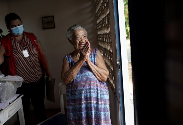 Maria do Carmo, 94, celebrates after getting a shot of China's Sinovac Corona Vac vaccine for COVID-19 at her home, as part of a program for seniors who cannot leave their homes in Marica, Rio de Janeiro state, Brazil, Monday, Feb. 22, 2021. (AP Photo/Silvia Izquierdo)