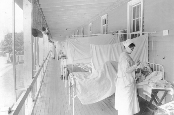 FILE - In this November 1918 photo made available by the Library of Congress, a nurse takes the pulse of a patient in the influenza ward of the Walter Reed hospital in Washington. In 1918, tens of thousands of U.S. soldiers died in World War I and hundreds of thousands of Americans died in a flu pandemic. Deaths rose 46% that year, compared with 1917. (Harris & Ewing/Library of Congress via AP, File)