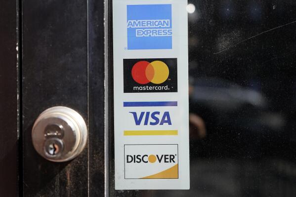 File - Credit card logos are displayed on a business's door, Monday, July 5, 2021, in Cambridge, Mass. As the Federal Reserve considers whether to raise interest rates again, credit card debt is already at record highs, and more people are carrying debt month to month. (AP Photo/Steven Senne, File)