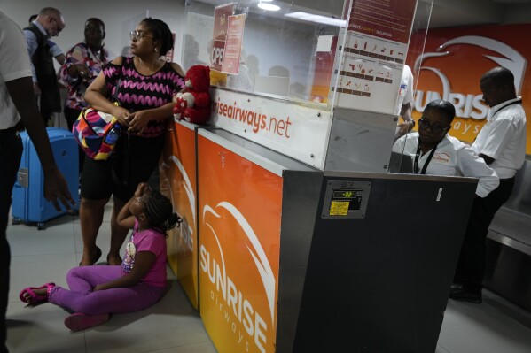Passengers wait at the counter of the Sunrise Airways airline at the Toussaint Louverture International Airport in Port-au-Prince, Haiti, Monday, May 20, 2024. Haiti's main international airport reopened Monday for the first time after gang violence forced authorities to close it in early March. (AP Photo/Ramon Espinosa)