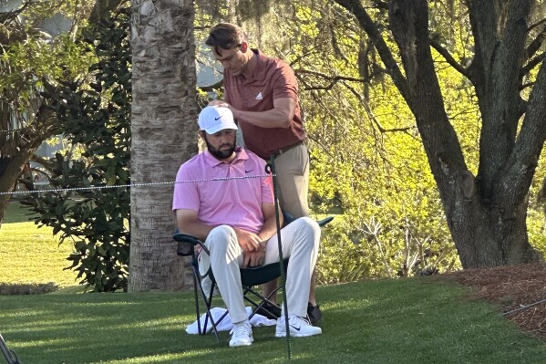 Scottie Scheffler, seated, gets treatment as he waits to tee off on the 14th hole during the second round of The Players Championship golf tournament Friday, March 15, 2024, in Ponte Vedra Beach, Fla. (AP Photo/Doug Ferguson)