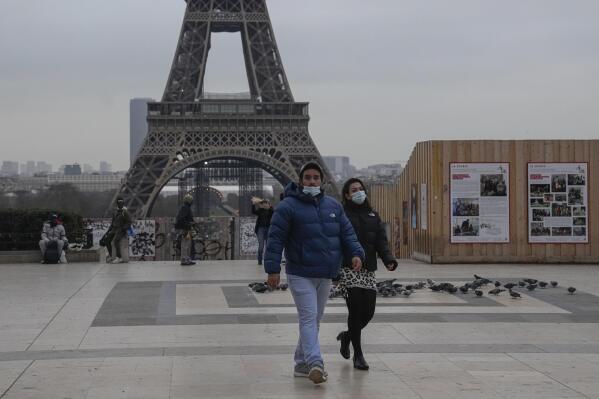 People wearing face masks to protect against COVID-19 cross the Trocadero Plaza in Paris, Wednesday, Dec. 15, 2021. Authorities in France want to accelerate vaccinations against the coronavirus before Christmas as infections surge and more people with COVID-19 seek medical attention. Eiffel Tower in the background. (AP Photo/Michel Euler)