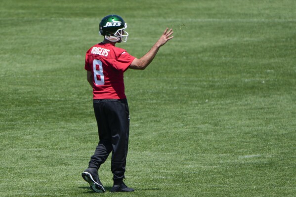 New York Jets quarterback Aaron Rodgers (8) throws some grass in the air during a practice at the NFL football team's training facility in Florham Park, N.J., Tuesday, May 21, 2024. (AP Photo/Seth Wenig)