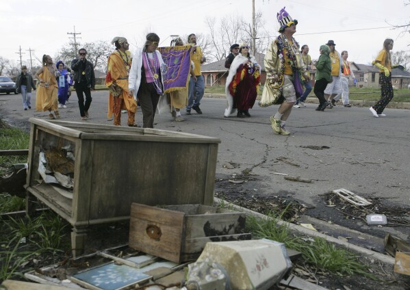 Members of the Krewe of Dreux marching club parade past piles of debris in the Gentilly neighborhood of New Orleans, Feb. 25, 2006. Keeping a tradition alive, the crew gathered for the 34th year in a row to parade through the hurricane-ravaged neighborhood. (AP Photo/Carolyn Kaster,file)