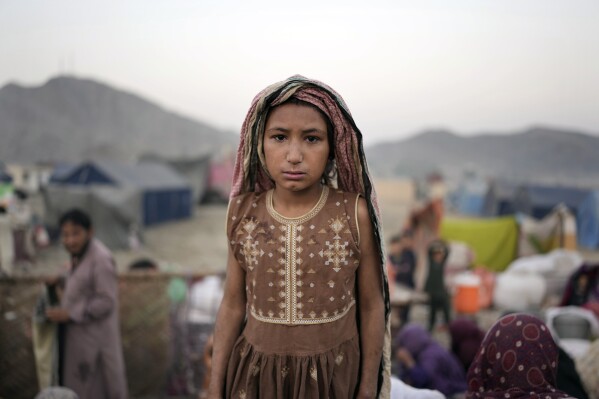 An Afghan refugee girl stands for a portrait in a camp near the Pakistan-Afghanistan border, in Torkham, Afghanistan, Saturday, Nov. 4, 2023. Many Afghan refugees arrived at the Torkham border to return home shortly before the expiration of a Pakistani government deadline for those who are in the country illegally, or face deportation. (AP Photo/Ebrahim Noroozi)