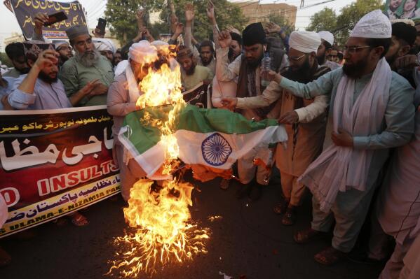 Supporters of religious groups burn a representation of Indian flag during a demonstration to condemn derogatory references to Islam and the Prophet Muhammad recently made by Nupur Sharma, a spokesperson of the governing Indian Hindu nationalist party, in Lahore, Pakistan, Thursday, June 9, 2022. (AP Photo/K.M. Chaudary)