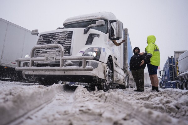 Over-the-road Amazon drivers stand by Matan Muur's semi-truck as they try to negotiate the jammed TA Travel Center and truck stop on Burlington Pike off I-75 in Florence, KY., 41042, Monday, Jan. 6, 2025. The weather and road conditions have forced trucks to get off the roads. (AP Photo/Carolyn Kaster)