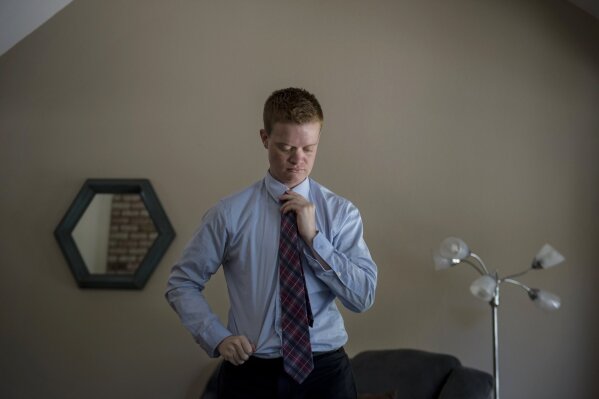 In this Aug. 30, 2019 photo, Evan Minton, who was denied a hysterectomy surgery at Mercy San Juan Medical Center related to his gender transition, adjusts his tie in Orangevale, Calif. Evans can go ahead with a discrimination lawsuit against the Catholic hospital that canceled his hysterectomy, an appeals court ruled, Tuesday, Sept. 17, 2019 (Jose Luis Villegas/The Sacramento Bee via AP)