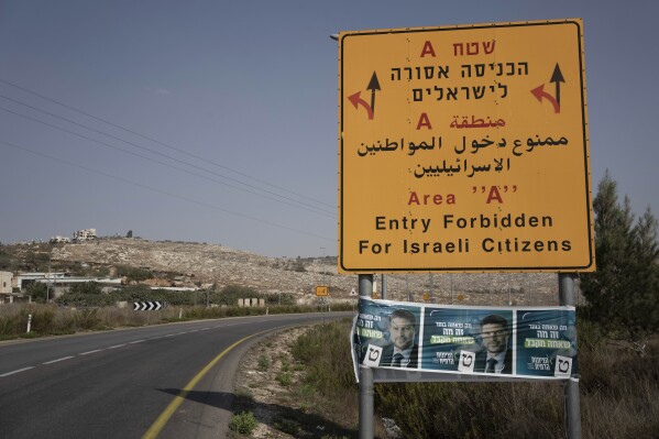 FILE - Campaign posters for far-right Israeli lawmaker Bezalel Smotrich, now the Minister of Finance, are strung across a road sign marking an entrance to an area under Palestinian control, near the West Bank town of Nablus, Sunday, Oct. 16, 2022. Smotrich assumed new powers from the military over the occupied territory this year. As the first minister to oversee civilian life in the West Bank, his role amounts to a recognition that Israel's occupation is not temporary, but permanent, observers say. (AP Photo/ Maya Alleruzzo, File)