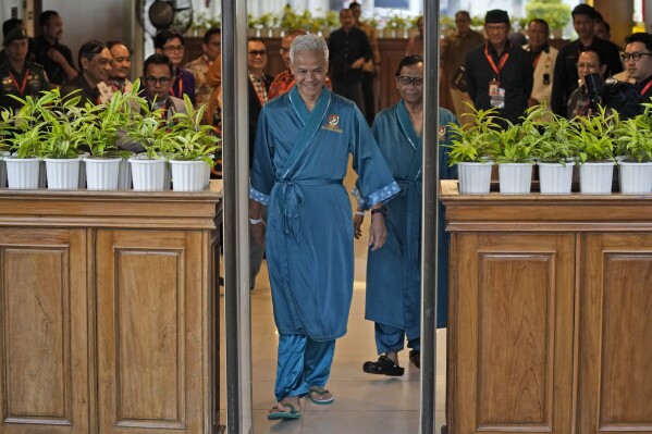 Presidential candidate Ganjar Pranowo, left, and his running mate Mohamad Mahfud, popularly known as Mahfud MD, walk to greet reporters prior to the medical check up required for their candidacy in the upcoming presidential election, at Gatot Subroto Army Hospital in Jakarta, Indonesia, Sunday, Oct. 22, 2023. The world's third-largest democracy is holding its legislative and presidential elections on Feb. 14, 2024. (AP Photo/Dita Alangkara)