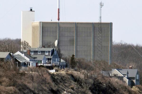 FILE - A portion of the Pilgrim Nuclear Power Station is visible beyond houses along the coast of Cape Cod Bay, in Plymouth, Mass., March 30, 2011. Pilgrim, which closed in 2019, was a boiling water reactor. Water constantly circulated through the reactor vessel and nuclear fuel, converting it to steam to spin the turbine. The water was cooled and recirculated, picking up radioactive contamination. (AP Photo/Steven Senne, File)