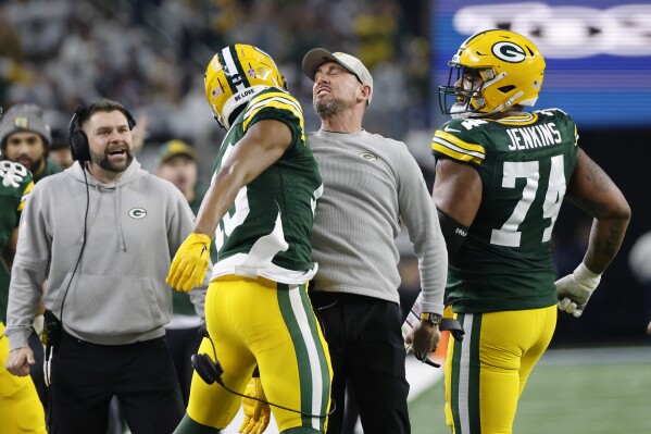 Green Bay Packers head coach Matt LaFleur, center right, bumps chests with wide receiver Dontayvion Wicks, center left, after Wicks caught a touchdown pass against the Dallas Cowboys during the first half of an NFL football game, Sunday, Jan. 14, 2024, in Arlington, Texas. (AP Photo/Michael Ainsworth)
