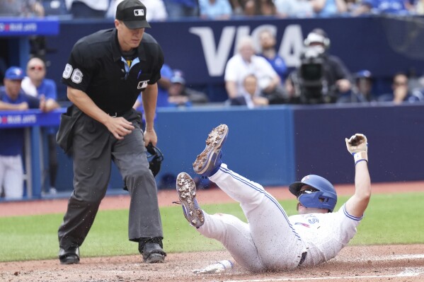 Toronto Blue Jays second baseman Davis Schneider scores on a wild pitch against the Kansas City Royals as umpire Chris Segal makes the call during the sixth inning of a baseball game in Toronto on Sunday, Sept. 10, 2023. (Nathan Denette/The Canadian Press via AP)