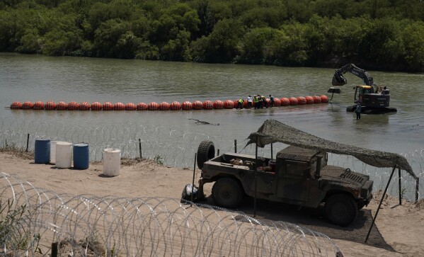 Workers assemble large buoys to be used as a border barrier along the banks of the Rio Grande in Eagle Pass, Texas, Tuesday, July 11, 2023. Texas Republican Gov. Greg Abbott has escalated measures to keep migrants from entering the U.S. He's pushing legal boundaries along the border with Mexico to install razor wire, deploy massive buoys on the Rio Grande and bulldozing border islands in the river. (AP Photo/Eric Gay)