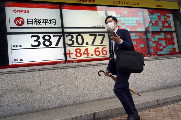 A person walks in front of an electronic stock board showing Japan's Nikkei 225 index at a securities firm Monday, May 27, 2024, in Tokyo. (AP Photo/Eugene Hoshiko)