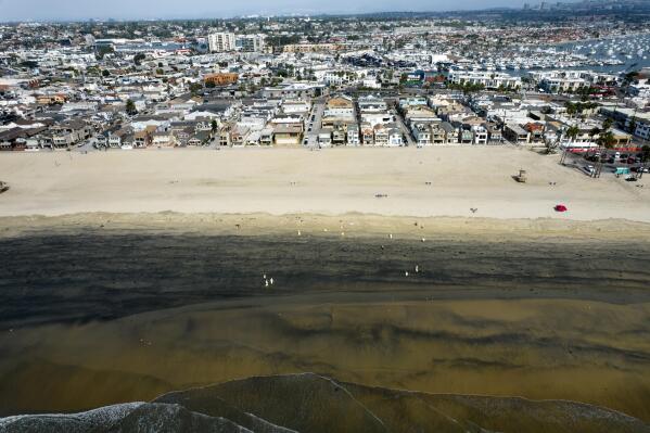FILE - In this Wednesday, Oct.6, 2021 aerial image taken with a drone, workers in protective suits clean the contaminated beach after an oil spill in Newport Beach, Calif.  California's uneasy relationship with the oil industry is being tested again by the latest spill to foul beaches and kill birds and fish off Orange County. (AP Photo/Ringo H.W. Chiu, File)