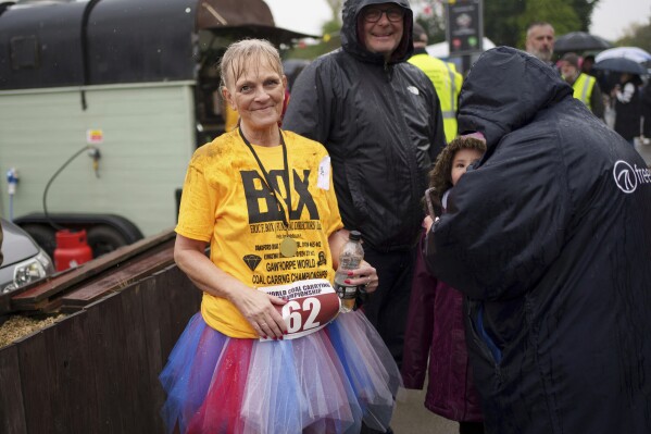 A competitor takes a drink after finishing her run in the World Coal Carrying Championships in Ossett, West Yorkshire, England, Monday, April 21, 2025. (AP Photo/Jon Super)